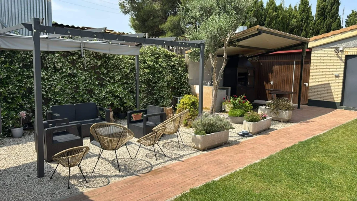 Rincón con sofás, butacas y plantas junto a la pérgola