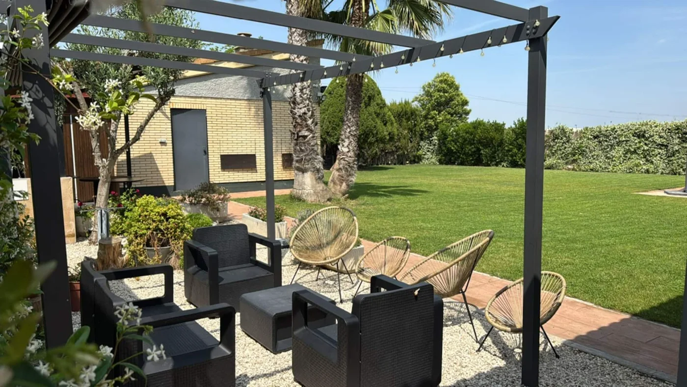 Zona chill-out con sofás y butacas bajo la pérgola