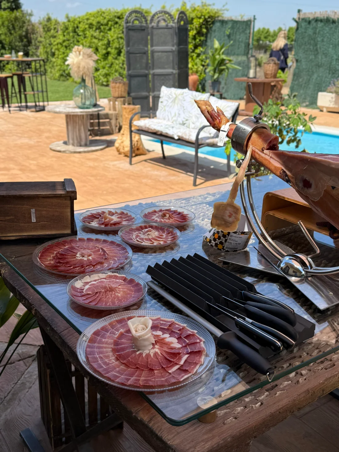 Mesa de jamón cortado junto a la piscina
