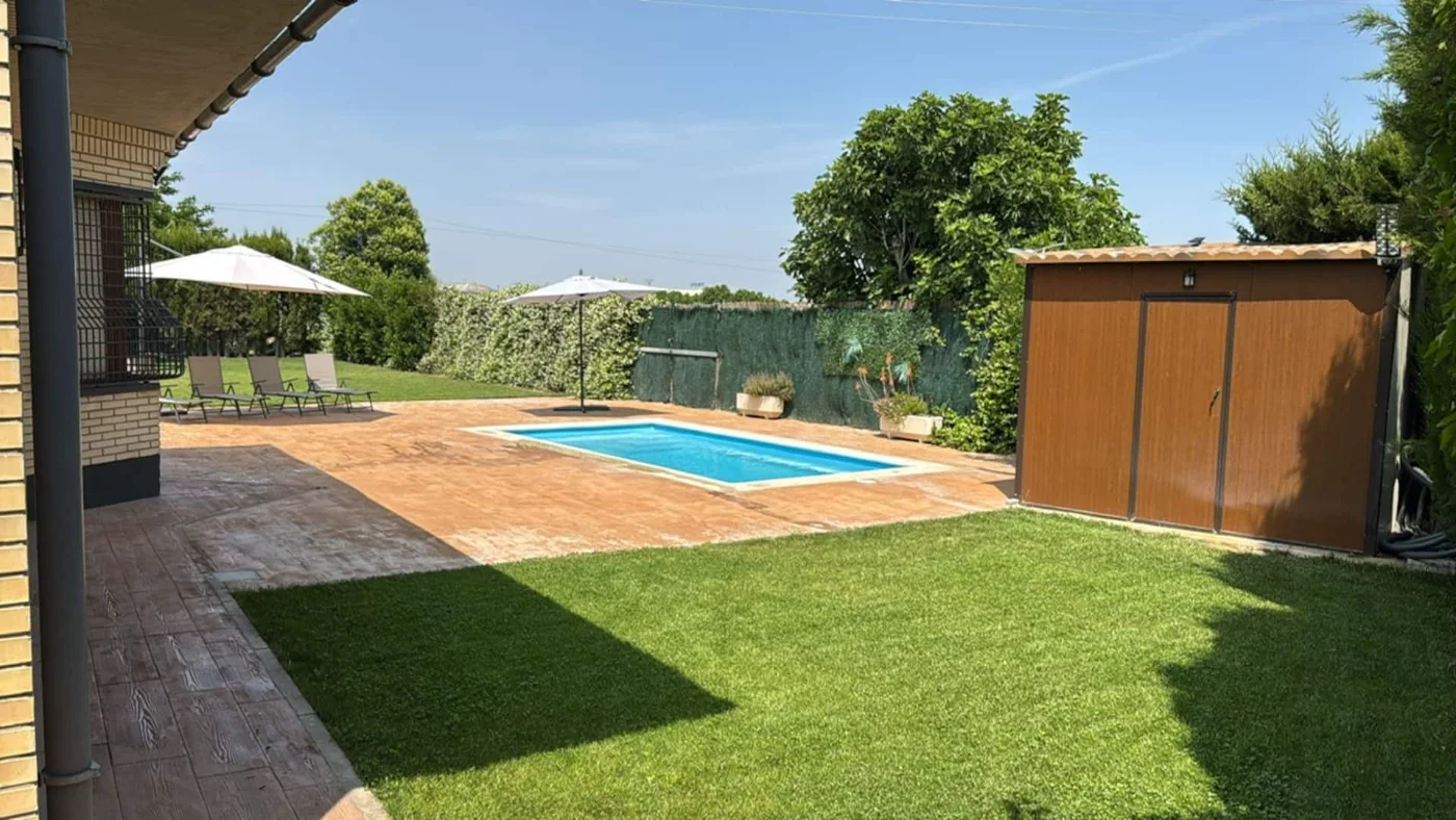 Piscina con sombrillas y césped